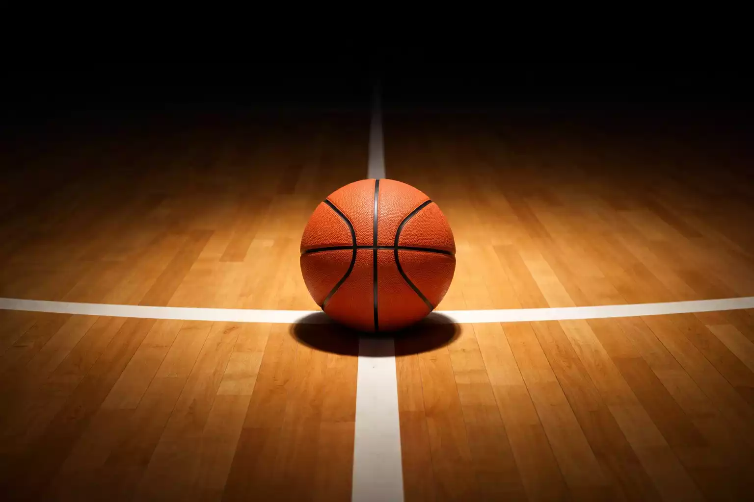 Close-up van een basketbal op een verlicht hardhouten veld met scherpe lijnen en schaduwen